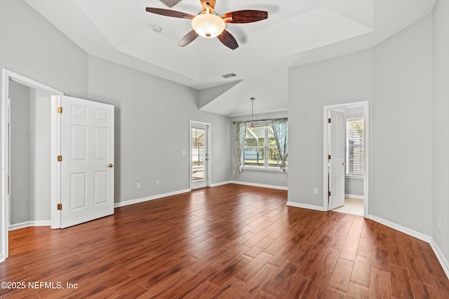 spare room with a tray ceiling, ceiling fan, and dark wood-type flooring