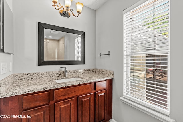 bathroom with a chandelier, vanity, and walk in shower