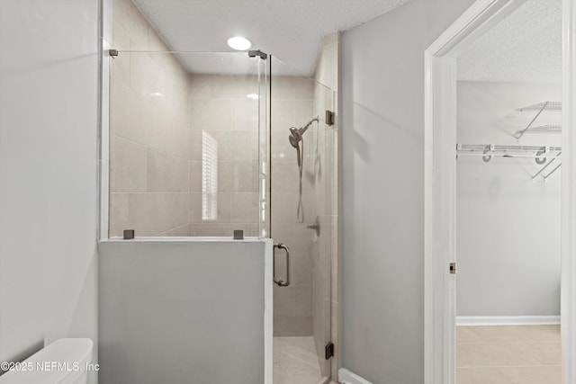 bathroom with a textured ceiling, toilet, and an enclosed shower