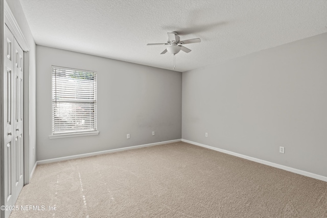 carpeted spare room featuring a textured ceiling and ceiling fan