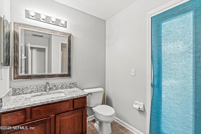 bathroom featuring tile patterned floors, vanity, toilet, and a textured ceiling