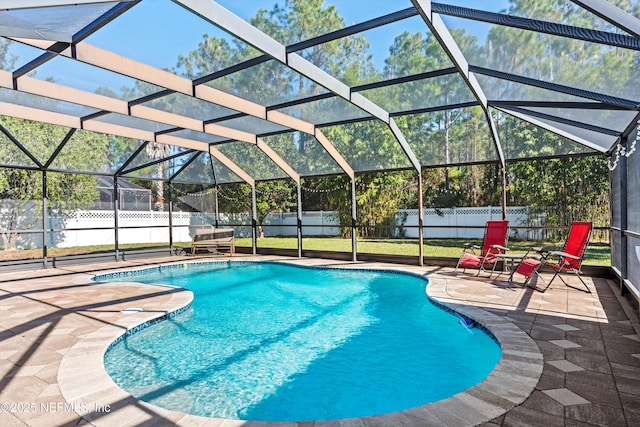 view of pool with glass enclosure, a yard, and a patio