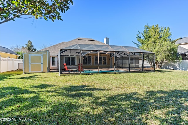 rear view of property with a lawn, a lanai, and a fenced in pool