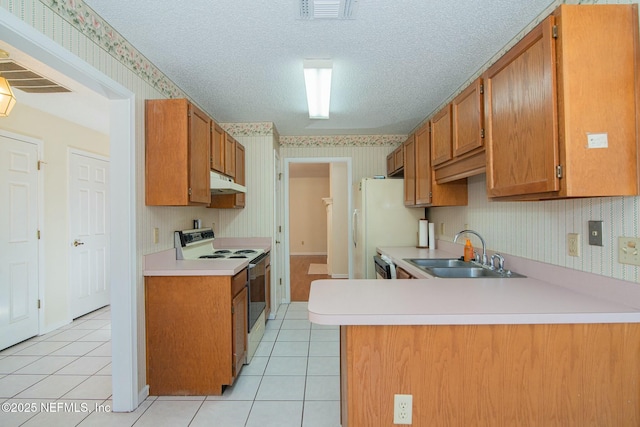 kitchen featuring kitchen peninsula, white appliances, light tile patterned flooring, a textured ceiling, and sink