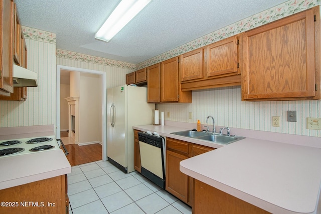 kitchen featuring sink, white appliances, light tile patterned floors, and a textured ceiling