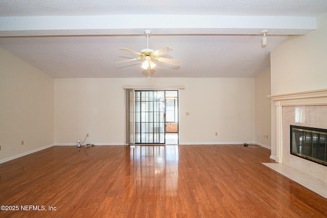 unfurnished living room featuring a textured ceiling, hardwood / wood-style floors, vaulted ceiling with beams, a fireplace, and ceiling fan