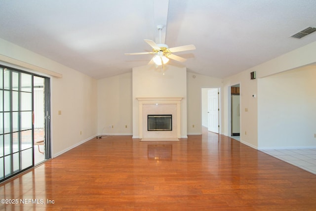 unfurnished living room featuring lofted ceiling, ceiling fan, a premium fireplace, and light hardwood / wood-style flooring