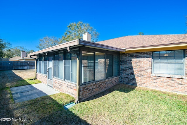 view of side of home with a sunroom and a lawn