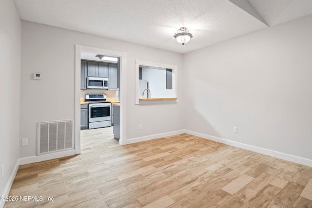 empty room featuring light wood-type flooring and a textured ceiling