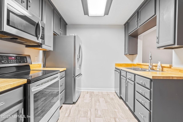 kitchen with gray cabinetry, light hardwood / wood-style floors, sink, and appliances with stainless steel finishes