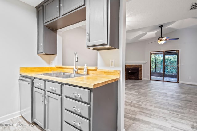 kitchen with stainless steel dishwasher, vaulted ceiling, ceiling fan, sink, and gray cabinets