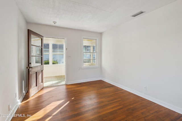 unfurnished room with a textured ceiling and dark hardwood / wood-style floors