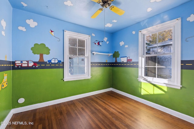 empty room featuring ceiling fan, plenty of natural light, and hardwood / wood-style floors