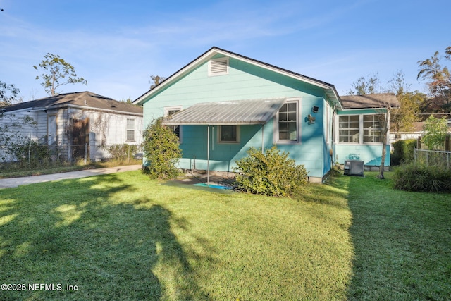 rear view of property with a yard, a sunroom, and central AC unit