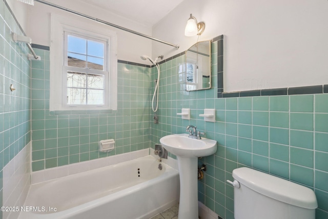 bathroom with toilet, tile walls, and tiled shower / bath combo