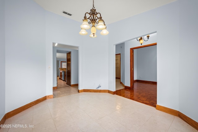 empty room with a chandelier and light tile patterned flooring