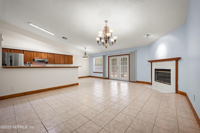 unfurnished living room with light tile patterned flooring, vaulted ceiling, a textured ceiling, and a notable chandelier