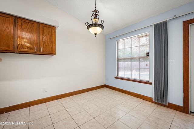 unfurnished dining area with vaulted ceiling and light tile patterned flooring