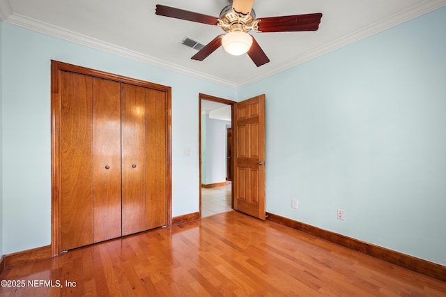 unfurnished bedroom with crown molding, ceiling fan, a closet, and light hardwood / wood-style flooring