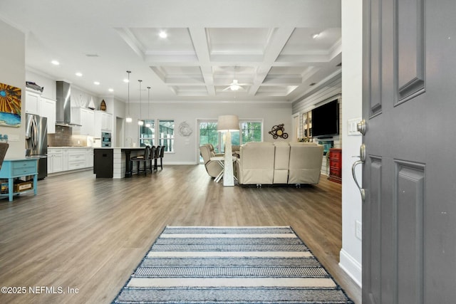 living room featuring beam ceiling, ornamental molding, ceiling fan, and coffered ceiling