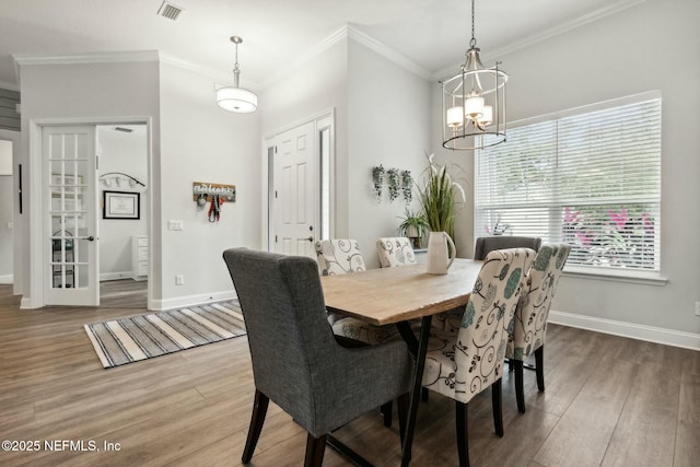 dining space featuring crown molding, an inviting chandelier, and hardwood / wood-style flooring