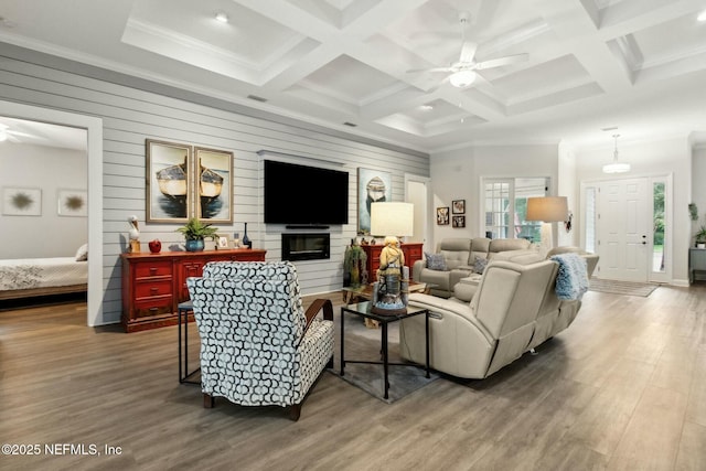 living room featuring a large fireplace, wood walls, hardwood / wood-style floors, and coffered ceiling