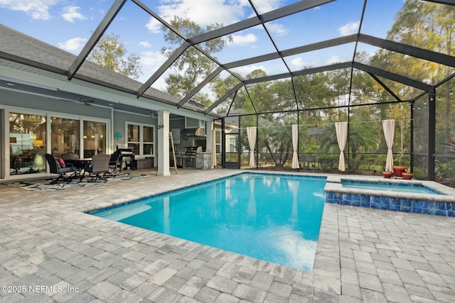 view of swimming pool with an outdoor kitchen, a patio area, an in ground hot tub, and glass enclosure