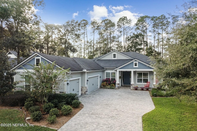 craftsman-style house featuring covered porch, a front yard, and a garage