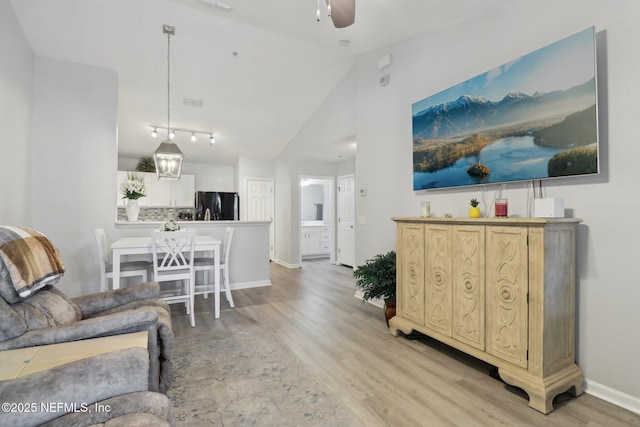 living room featuring light hardwood / wood-style floors, vaulted ceiling, and ceiling fan