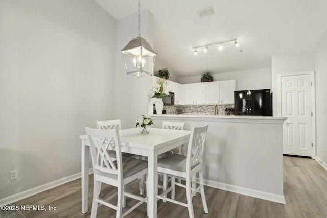 dining area with light hardwood / wood-style floors and vaulted ceiling