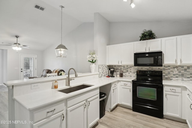 kitchen featuring pendant lighting, lofted ceiling, black appliances, sink, and kitchen peninsula