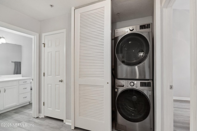 washroom featuring light wood-type flooring and stacked washer and clothes dryer