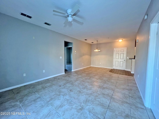 tiled empty room with ceiling fan with notable chandelier