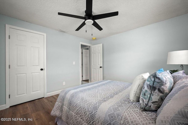 bedroom featuring dark wood-type flooring, ceiling fan, and a textured ceiling