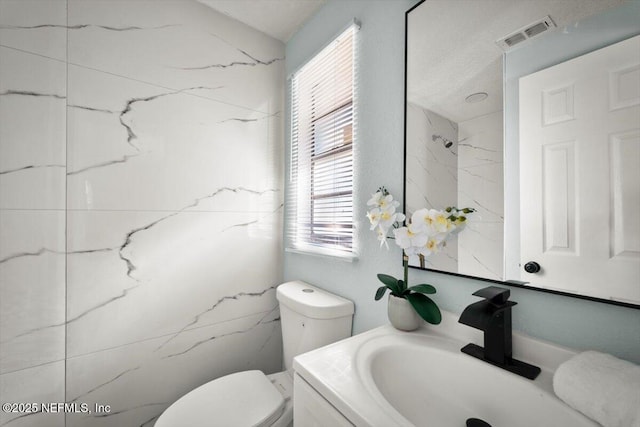 bathroom featuring toilet, vanity, and a healthy amount of sunlight