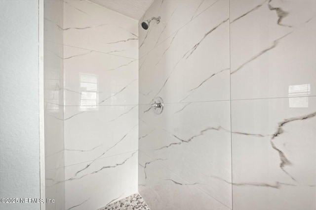 bathroom featuring a textured ceiling and a tile shower