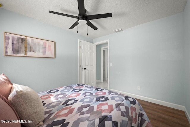 bedroom featuring ceiling fan, dark hardwood / wood-style flooring, and a textured ceiling