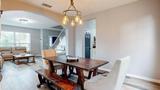 dining space with light hardwood / wood-style floors and a notable chandelier