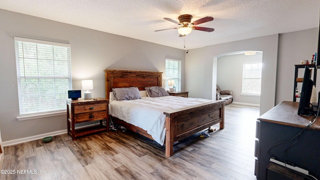 bedroom with hardwood / wood-style flooring, ceiling fan, and a textured ceiling