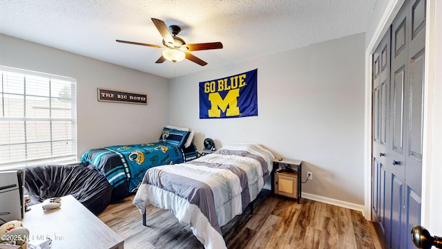 bedroom featuring ceiling fan, wood-type flooring, a textured ceiling, and a closet