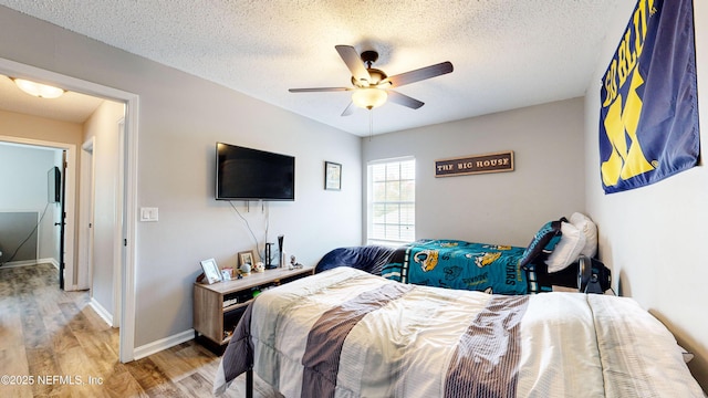 bedroom with ceiling fan, wood-type flooring, and a textured ceiling