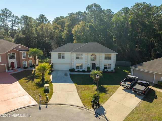 view of front facade featuring a front yard, concrete driveway, a view of trees, and an attached garage