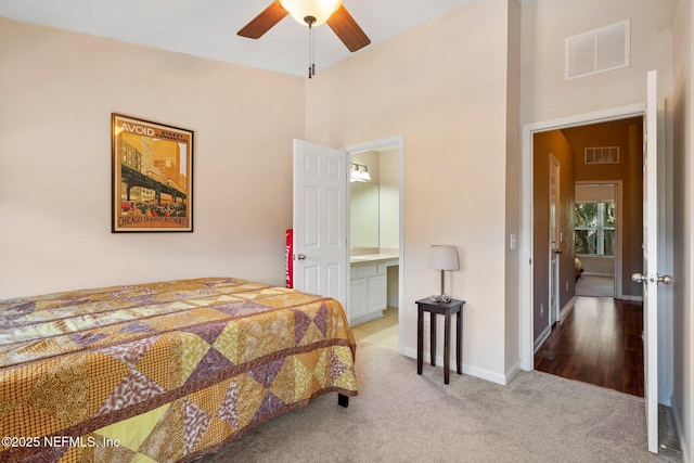 bedroom featuring ceiling fan, light colored carpet, and connected bathroom