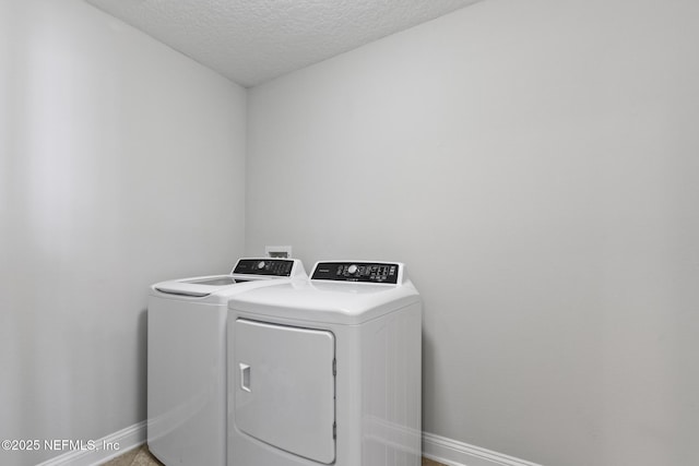 washroom with washing machine and clothes dryer and a textured ceiling