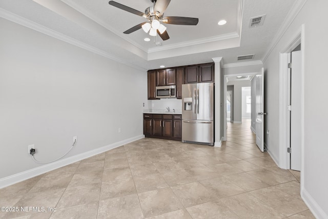 kitchen with dark brown cabinetry, stainless steel appliances, a tray ceiling, ceiling fan, and crown molding