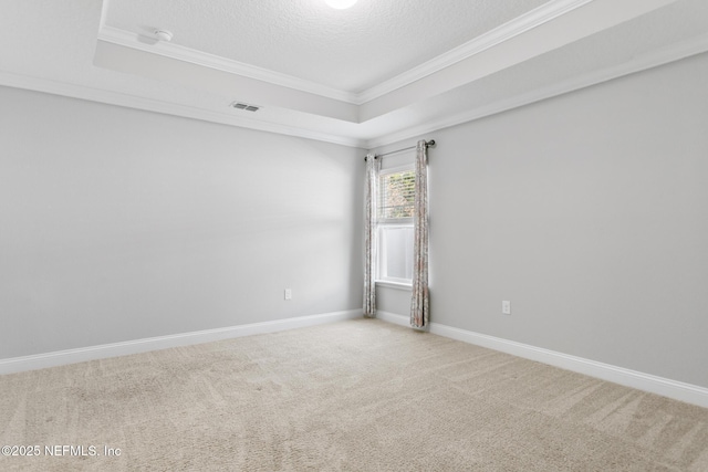 carpeted spare room with a textured ceiling, a raised ceiling, and crown molding