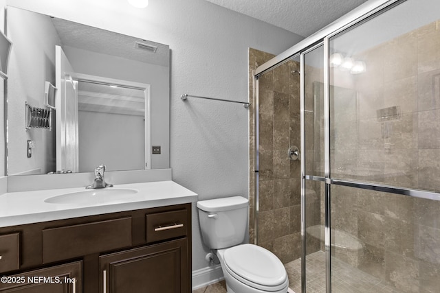 bathroom featuring vanity, toilet, a shower with door, and a textured ceiling