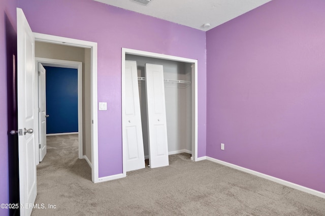 unfurnished bedroom featuring light carpet and a closet