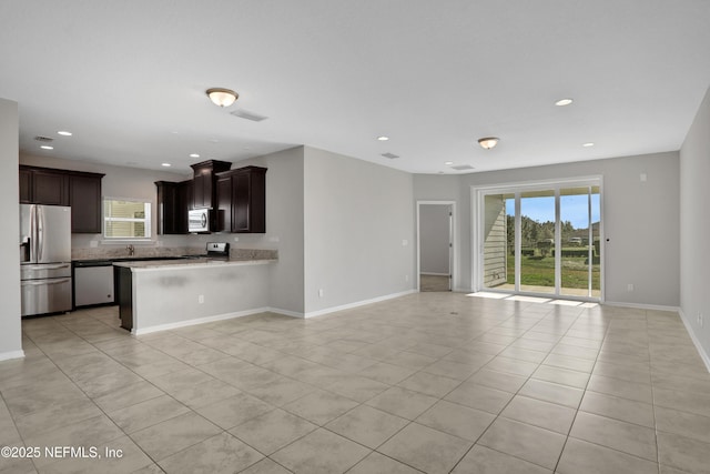 kitchen featuring kitchen peninsula, appliances with stainless steel finishes, light tile patterned floors, and plenty of natural light