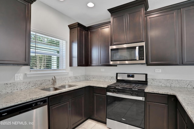 kitchen with dark brown cabinetry, light stone countertops, sink, light tile patterned floors, and appliances with stainless steel finishes